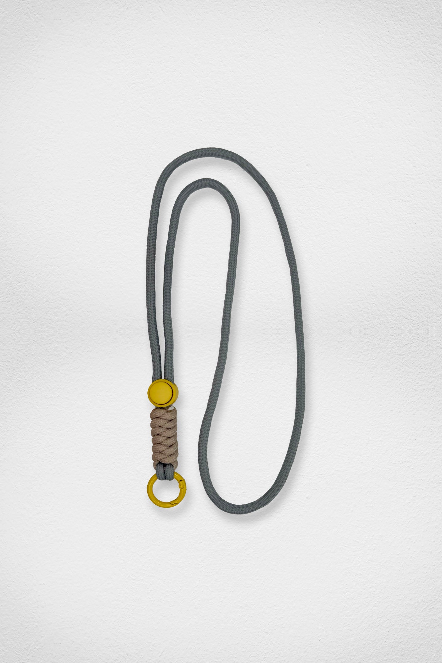 Gray lanyard with a brown braided section and yellow metal ring on a light gray background